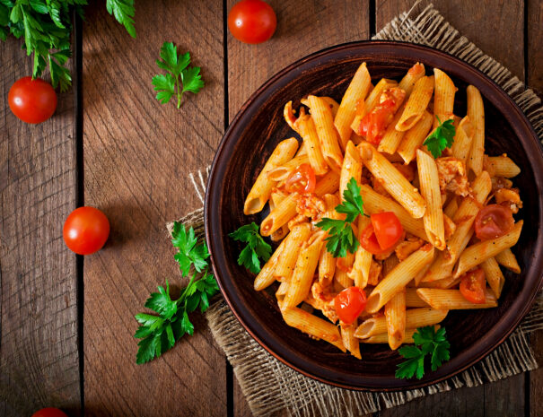 Penne pasta in tomato sauce with chicken and tomatoes  on a wooden table